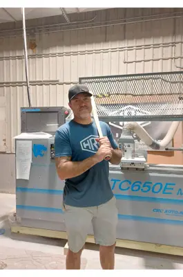 Man standing in front of machinery with baseball bat