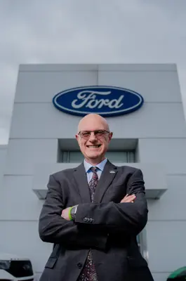 Man standing in front of a ford sign