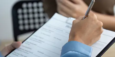 hand filling out a form with a pen