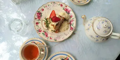 Table with tea cups, teapot, and slice of cake on plate