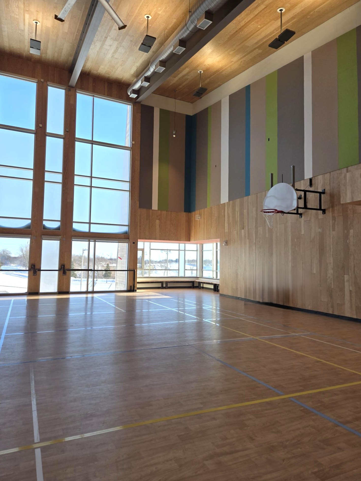 Gymnasium with large wall to ceiling windows and basketball net