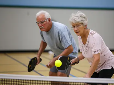 Senior woman and man playing pickleball together