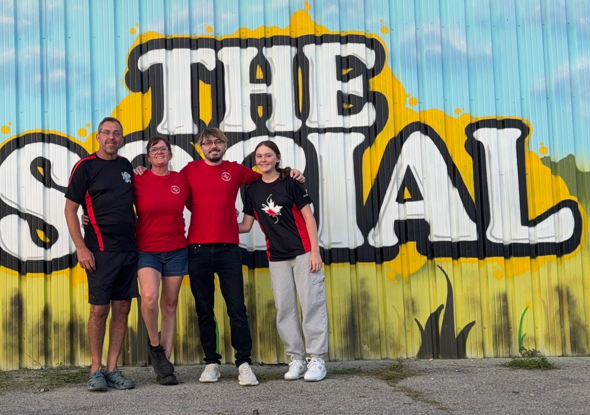 4 people standing in front of a building with a mural 