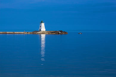 A lighthouse stands in relief from the brilliant blue waters of Haldimand County