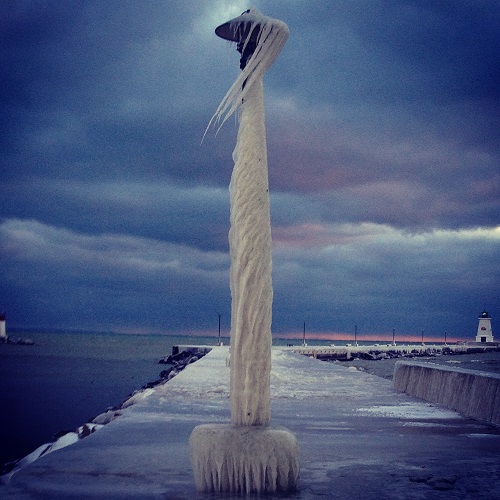 A light post drapped in a sheet of ice that twists and bends around it, sculpted by the elements