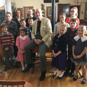 A picture of a class of children and their teacher in a one room schoolhouse