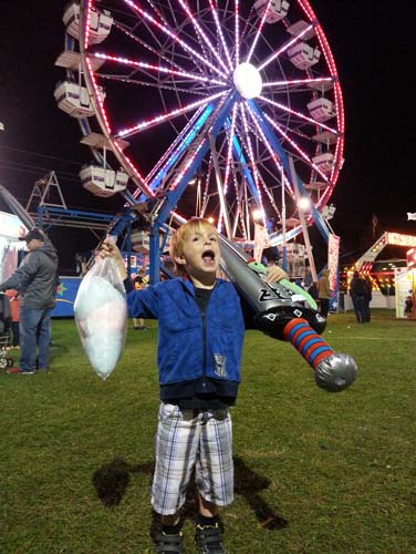 An image of a young boy celebrating his wins at the fair grounds midway