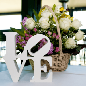 White block letters that spell love sit on table in front of a basket of flowers
