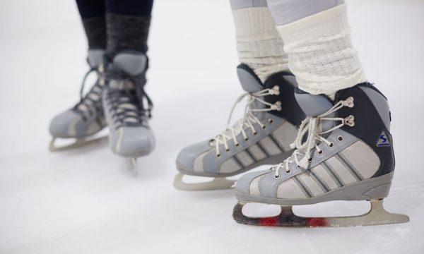 Two pairs of women's figure skates on ice.