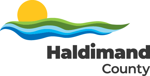 Haldimand County logo. A yellow sun rising or setting atop green and blue waves. Haldimand County in black lettering below.