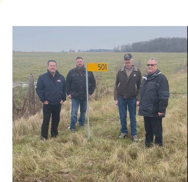 Individuals associated with the farm 911 Emily Project stand beside a newly installed yellow Farm 911 sign. From left to right:rogram sponsors Darcy Johnson (Erie Mutual), Richard Blyleven (Christian Farmers Federation of Ontario local chapter), and Councillor John Metcalfe (Council representative for Haldimand County’s Agriculture Advisory Committee). Henk Lise is also the Chair of Haldimand County’s Agriculture Advisory Committee and President of the Haldimand Federation of Agriculture.