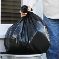 Putting a garbage bag in a bin